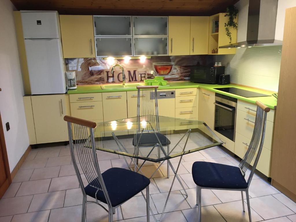 a kitchen with a glass table and two chairs at Horváth Apartmanház in Szigliget