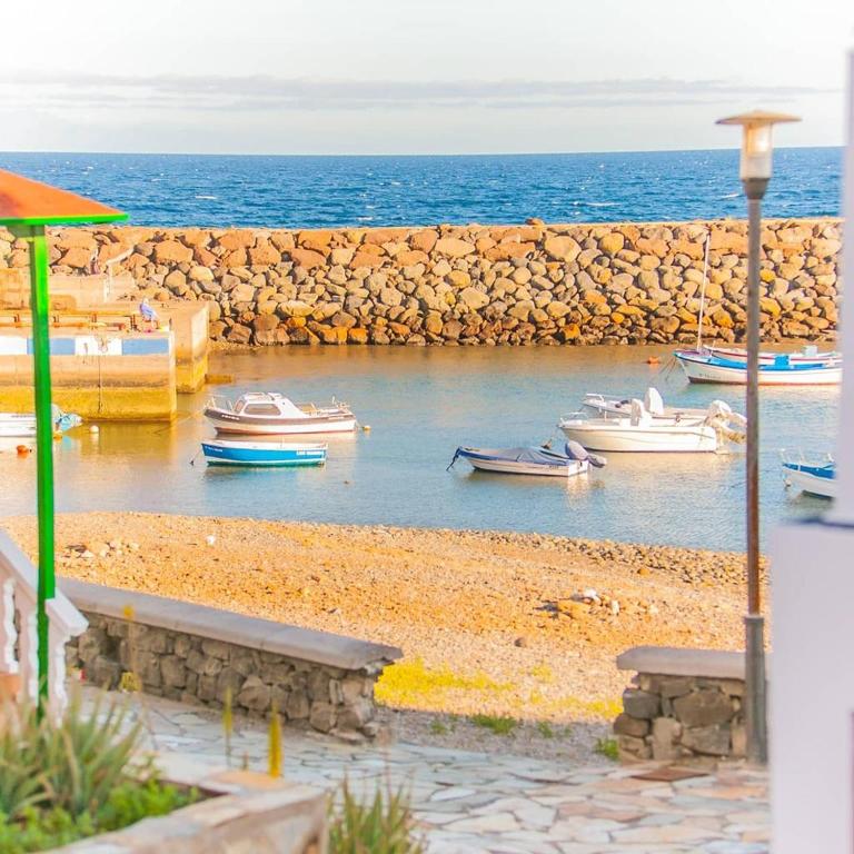 a group of boats in the water near a stone wall at Beach House Tajao in La Jaca