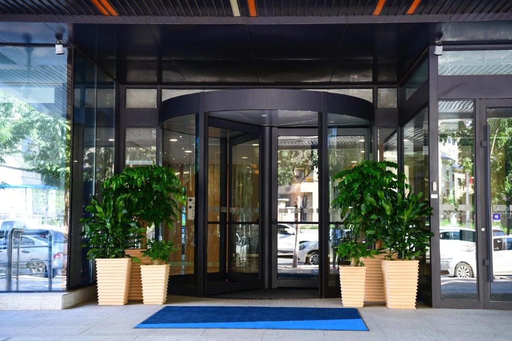 a glass building with two potted plants in front of it at Holiday Inn Express Changchun High-Tech Zone by IHG in Changchun