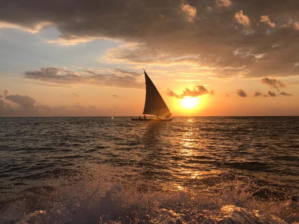 a sail boat in the ocean at sunset at Bahari Pori Resort in Pangani