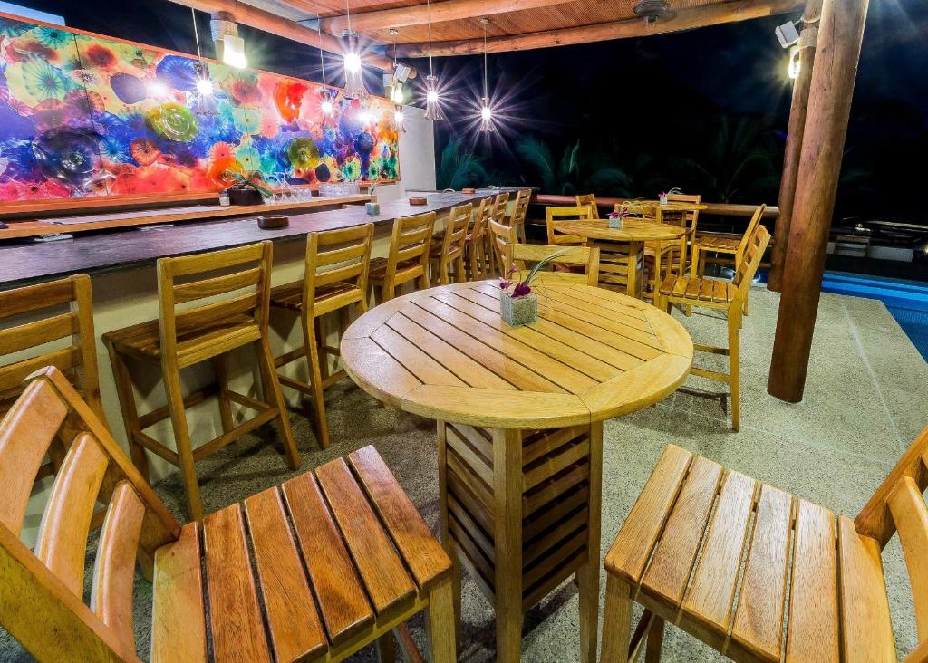 Outdoor covered bar with wooden tables, chairs, colorful artwork, and nighttime lighting.