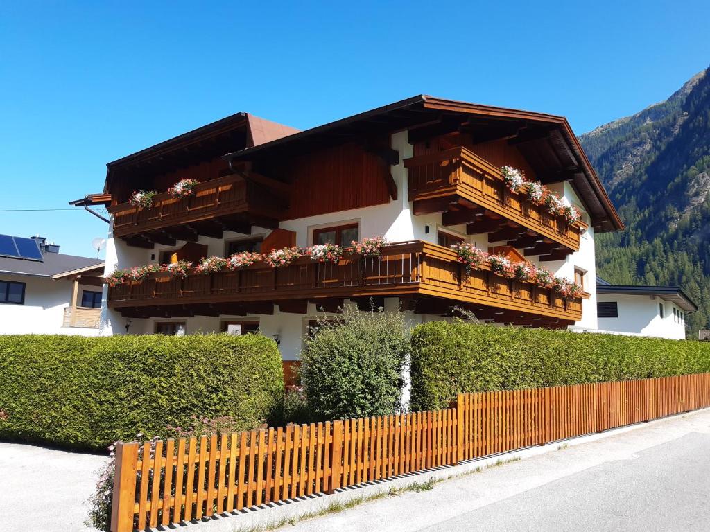 ein Gebäude mit einem Balkon mit Blumen darauf in der Unterkunft Gästehaus Helga in Längenfeld