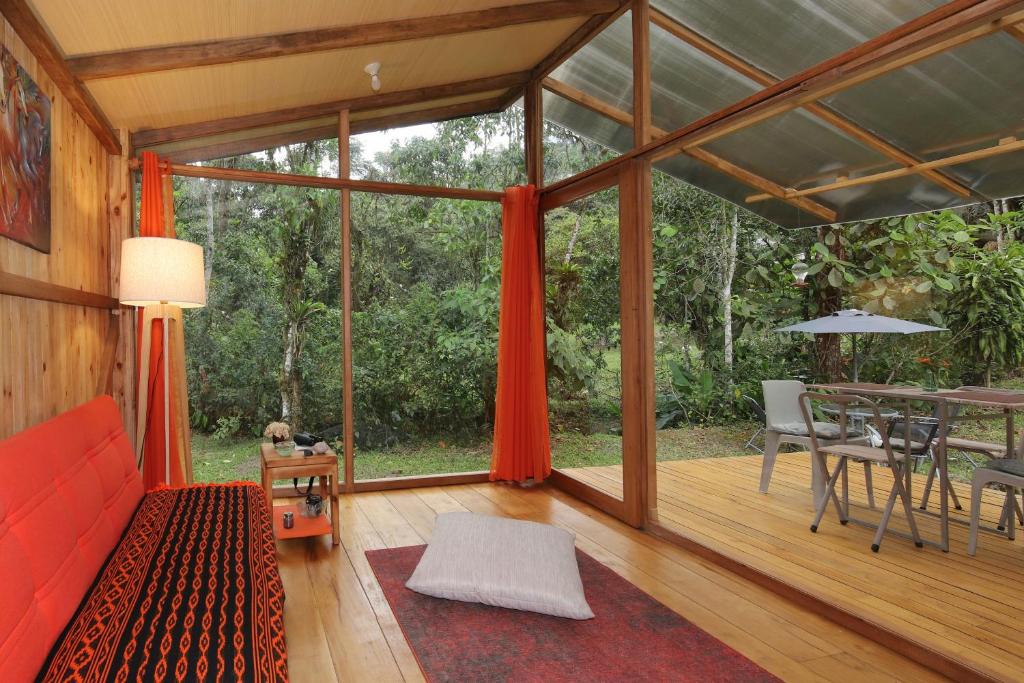 a living room with a red couch and a table at Mindo Eco Suite con Rio y Cascada in Mindo