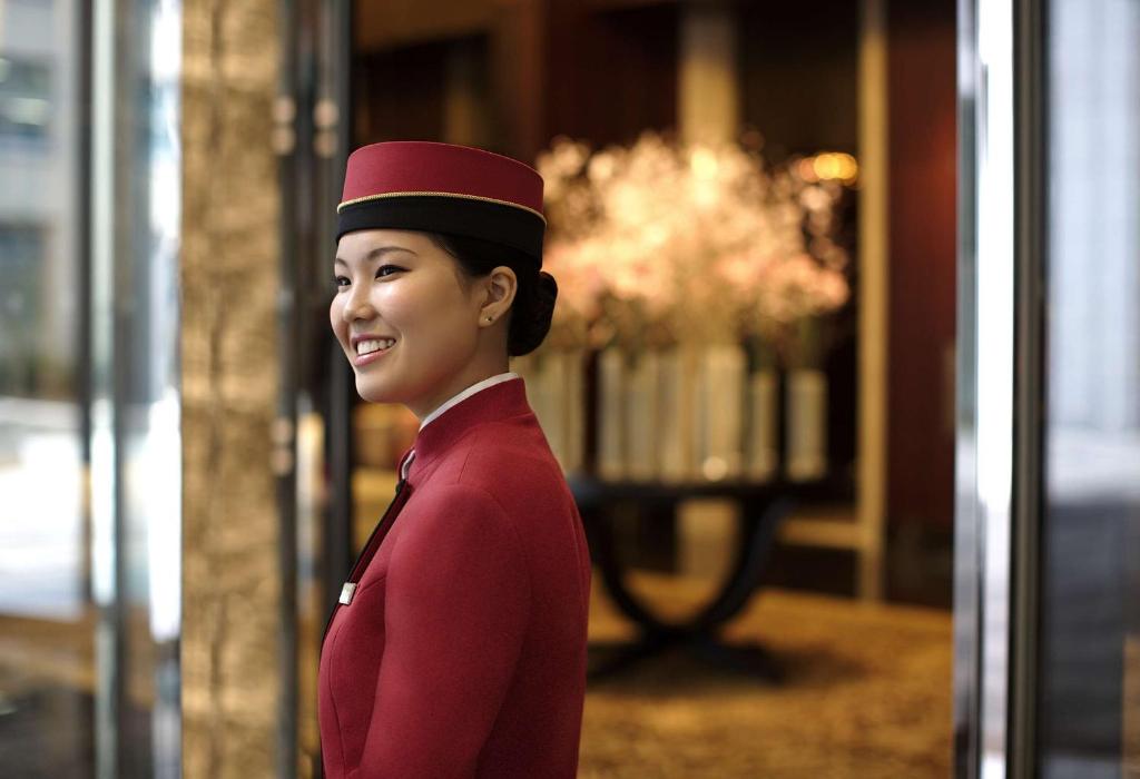 a woman in red uniform standing in front of a window at Shangri-La Tokyo in Tokyo