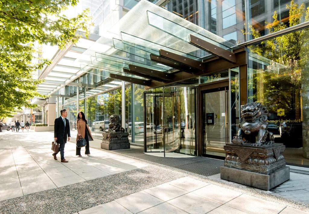 un homme et une femme marchant devant un bâtiment dans l'établissement Shangri-La Vancouver, à Vancouver