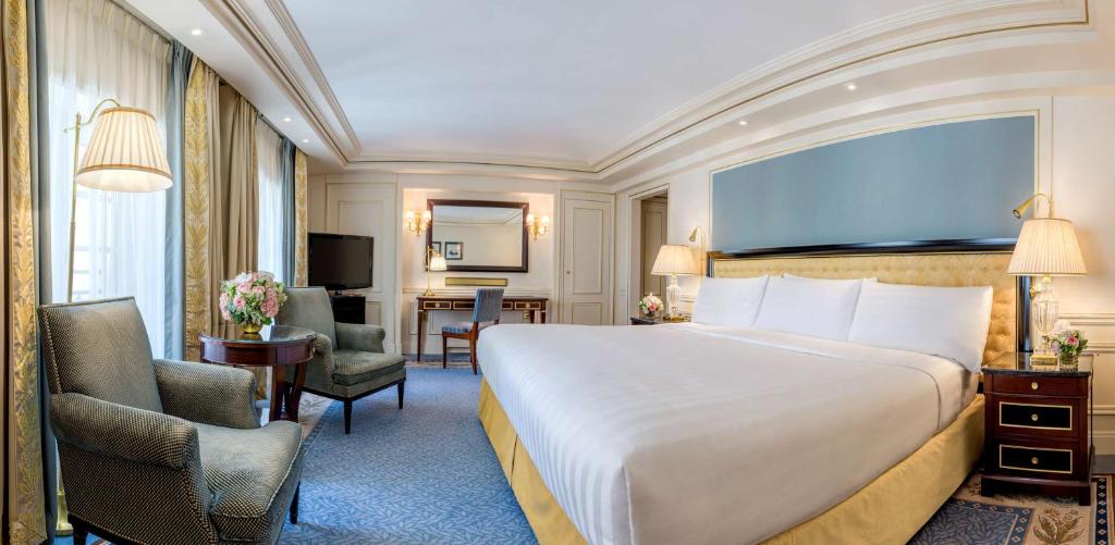 a hotel room with a large bed and a desk at Shangri-La Paris in Paris