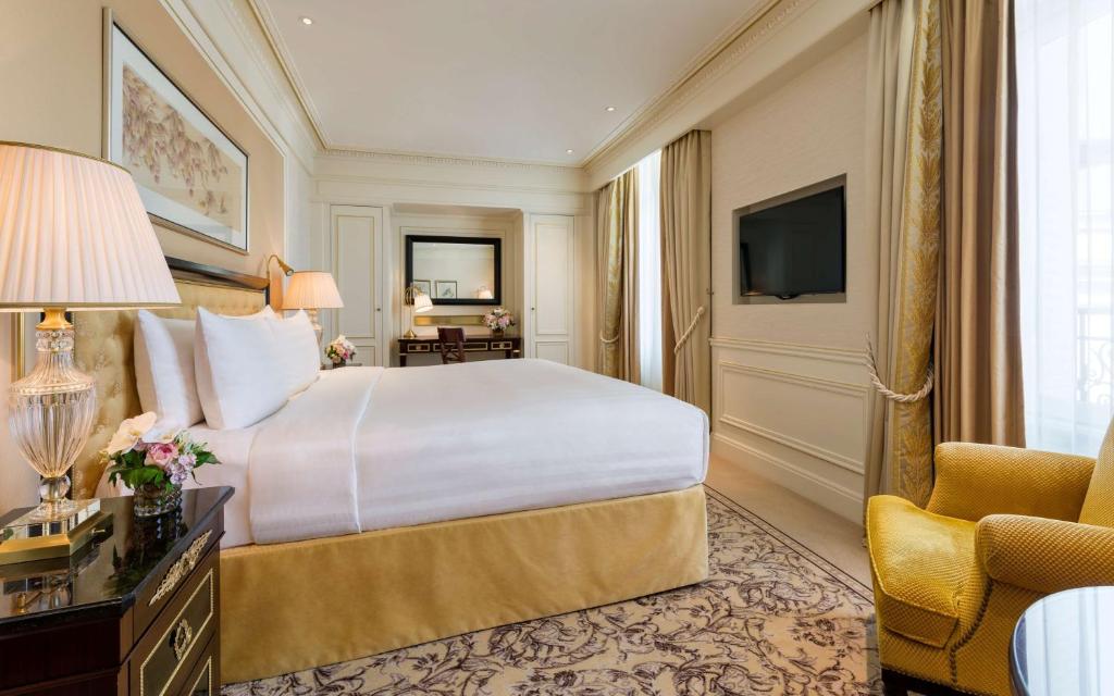 a hotel room with a large bed and a chair at Shangri-La Paris in Paris