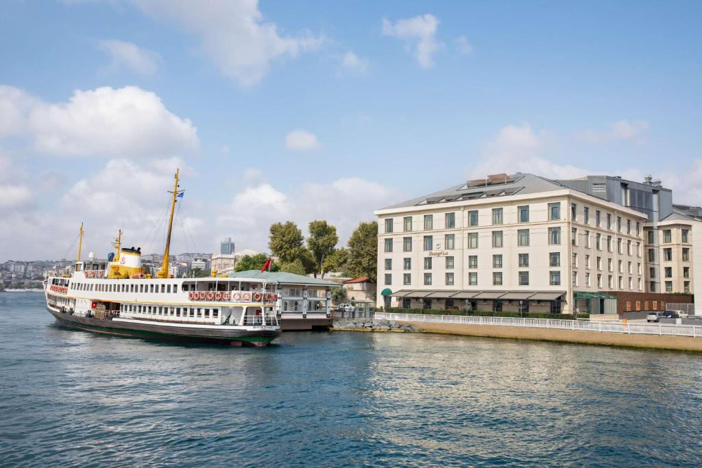 a large boat in the water next to a building at Shangri-La Bosphorus, Istanbul in Istanbul