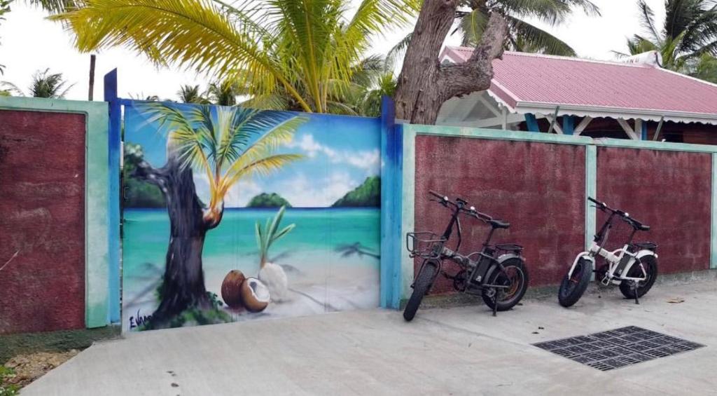 two bikes parked in front of a wall with a mural at kokopoirier in Terre-de-Haut