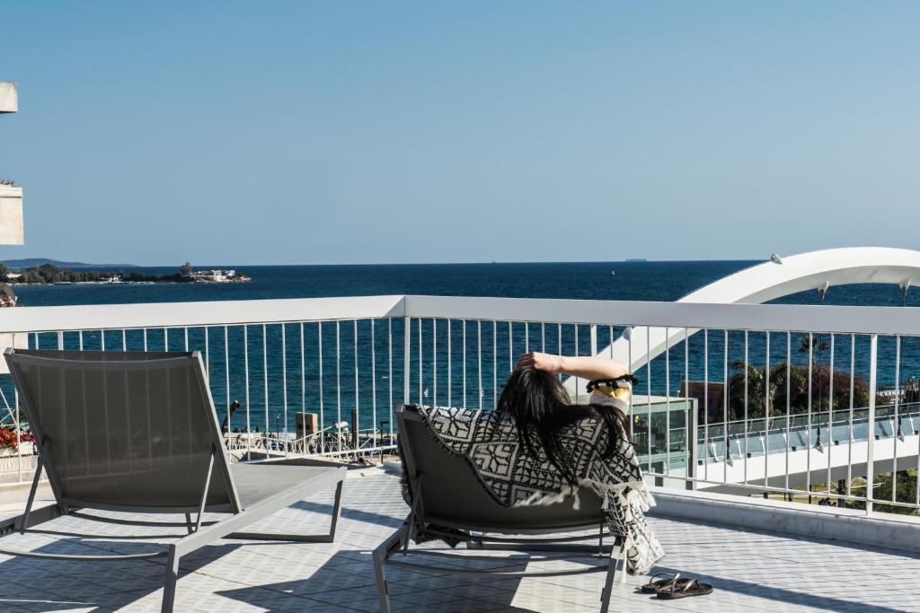een vrouw in een stoel op een balkon met uitzicht op de oceaan bij Sea View Beach Penthouse - Athens Coast in Athene