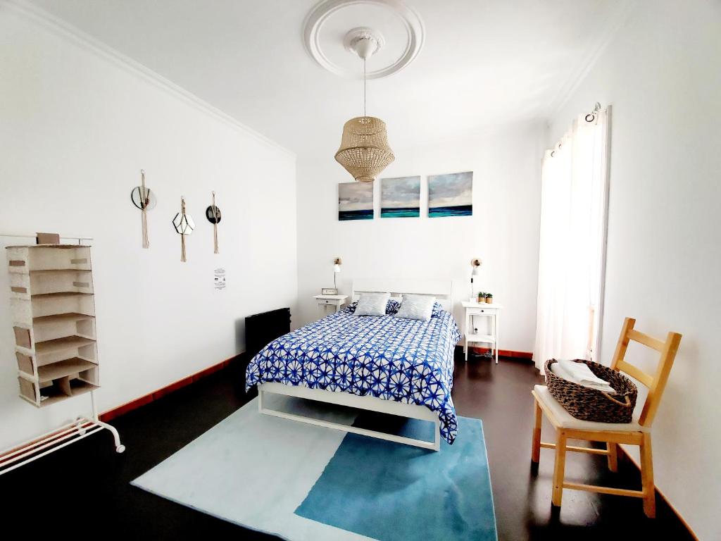 a white bedroom with a bed and a chair at Cozy Beach House in Ribeira Grande