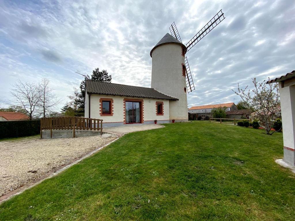 a house with a windmill in a yard at LE MOULIN DES GARDES in Saint-Georges-du-Puy-de-la-Garde