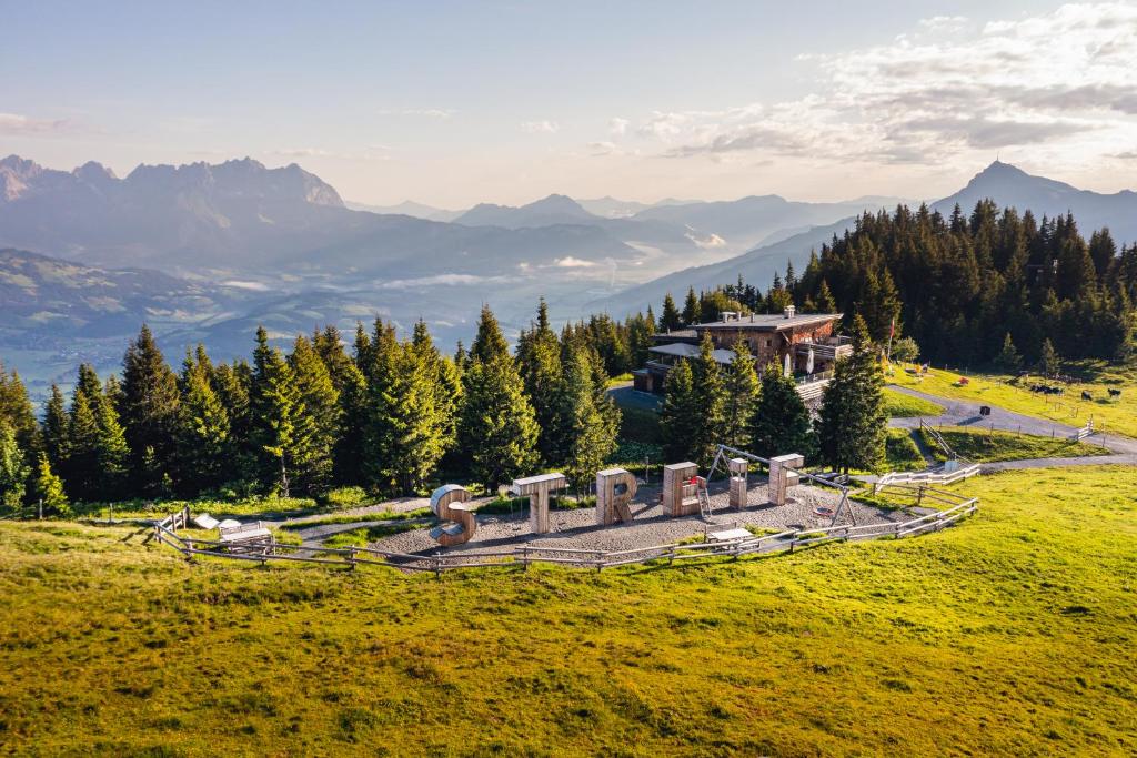 uma casa numa colina com montanhas ao fundo em Berghaus Tirol em Kitzbühel