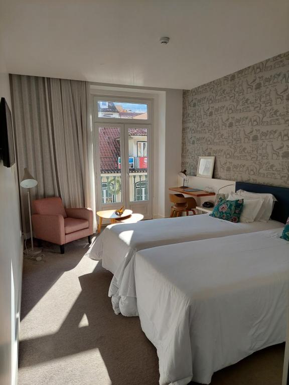 a bedroom with a large white bed and a chair at Augusta Boutique House in Lisbon