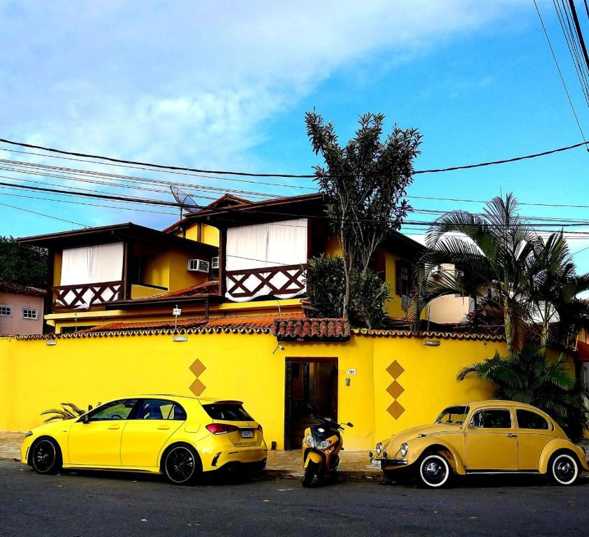 deux voitures jaunes garées devant un bâtiment jaune dans l'établissement MAI Chameguin Hospedagens Paraty, à Parati