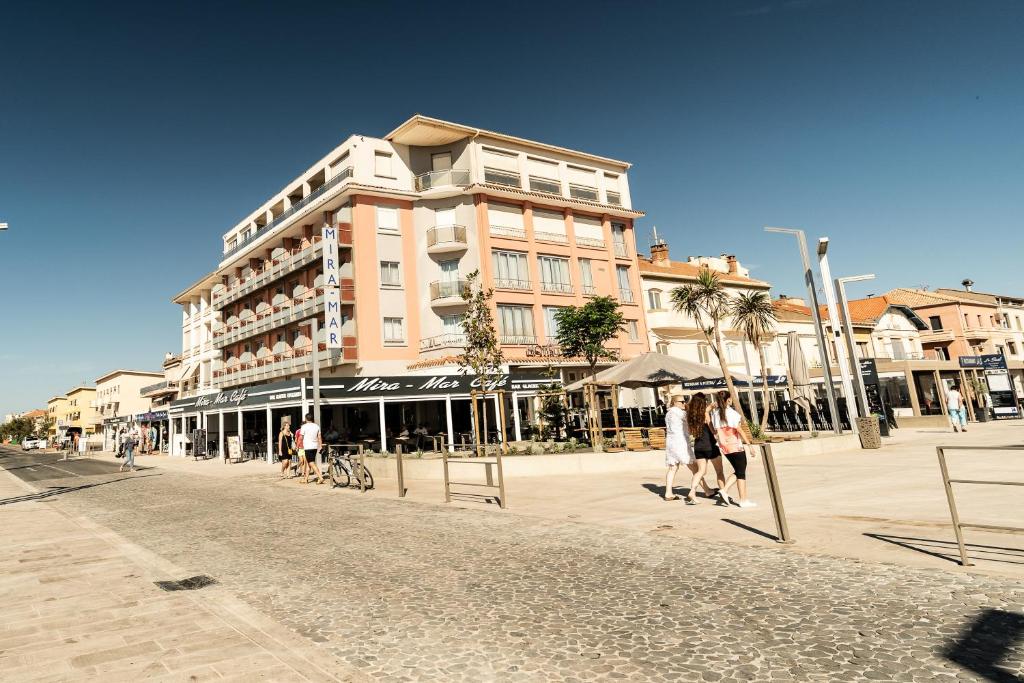 a building on a street with people walking in front of it at Hotel Mira-Mar in Valras-Plage