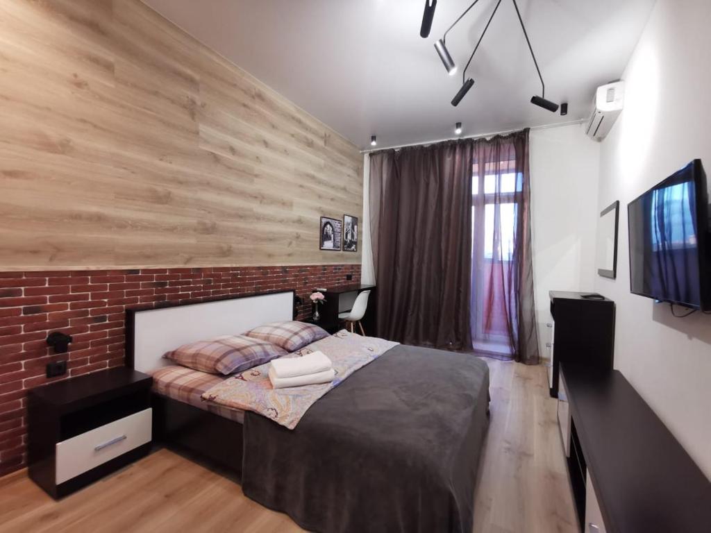 a bedroom with a bed and a brick wall at ЖК Династия LOFT in Yaroslavl