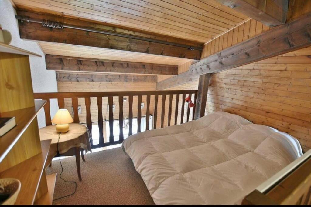 a bed in a room with a wooden wall at Superbe appartement au centre de Samoens in Samoëns