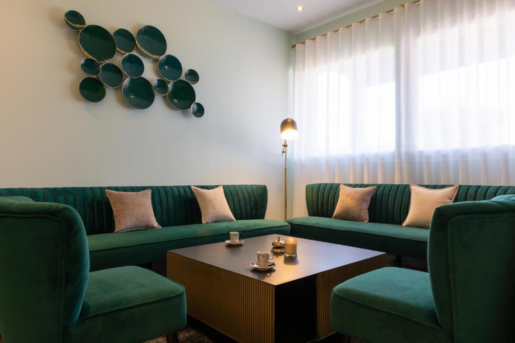 a living room with green couches and a coffee table at The Originals Boutique, Hôtel Porte de Dieppe in Saint-Aubin-sur-Scie