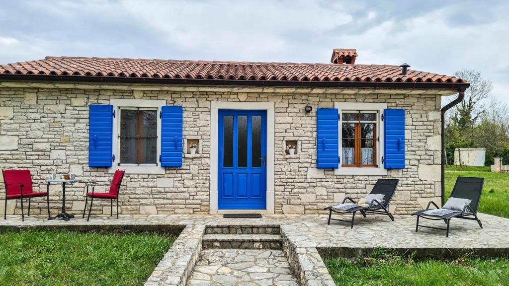 a small stone house with blue doors and chairs at House Avena with spa & gym in Labin