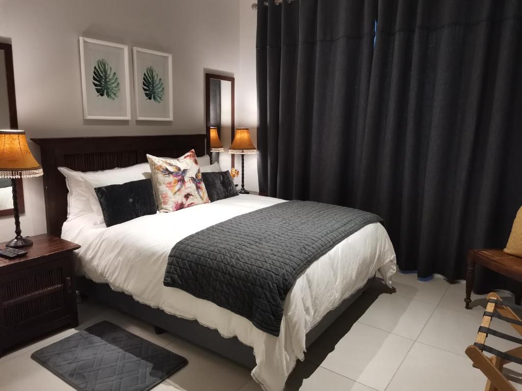 a bedroom with a large bed with black curtains at Brewer Place in Port Elizabeth