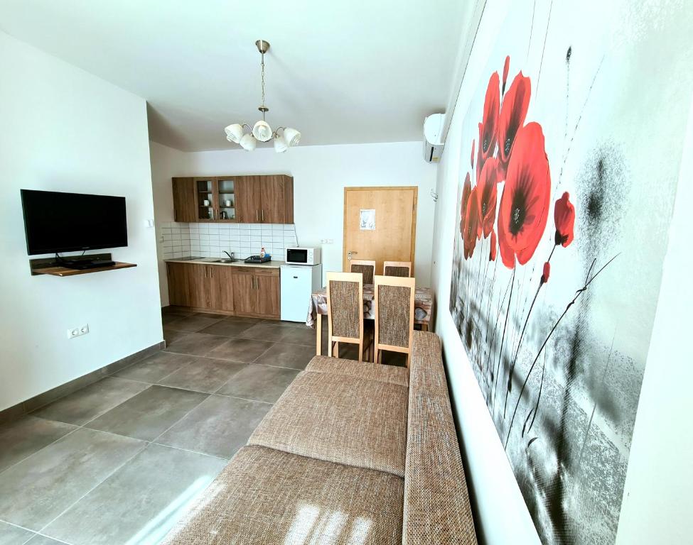 a living room with a kitchen with red flowers on the wall at Regina Apartman Hegykő in Hegykő
