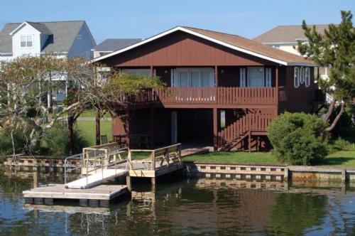 una casa sentada en el agua con un muelle en Dawn's Delight, en Holden Beach