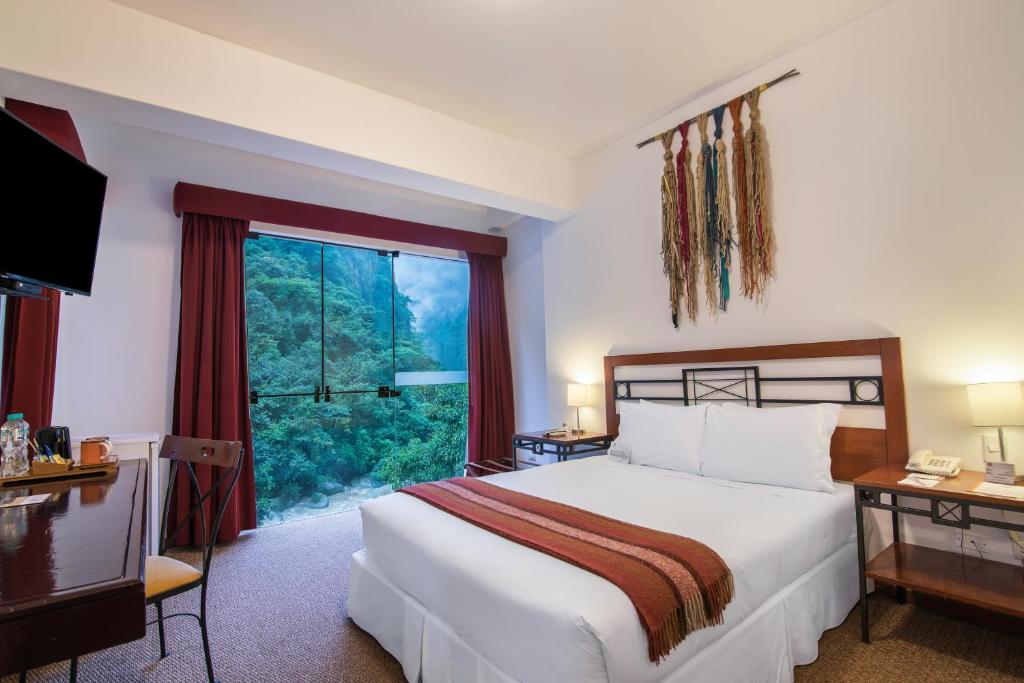 
a hotel room with a bed, table and window at Tierra Viva Machu Picchu Hotel in Machu Picchu

