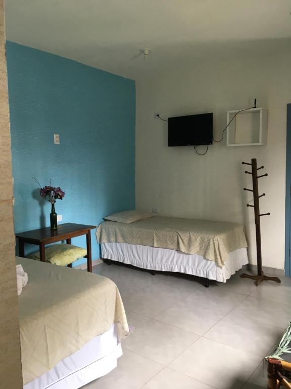 a room with two beds and a tv on the wall at Residencial Beira Mar Cananéia in Cananéia