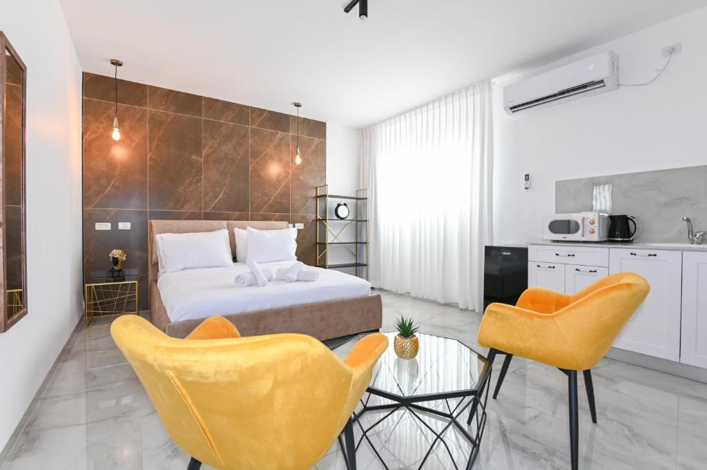 een slaapkamer met een bed en 2 gele stoelen bij Lake Mansion Boutique Apartments in Tiberias