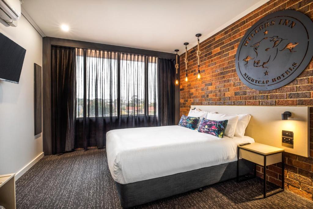 Habitación de hotel con cama y pared de ladrillo en Nightcap at Millers Inn en Altona