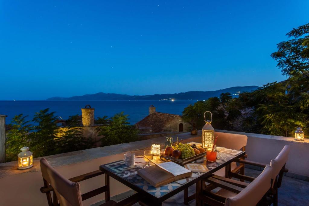 uma mesa num pátio com vista para o oceano em Myrsini's Castle House - Comfortable Residence with Large Balcony & Sea View em Monemvasia