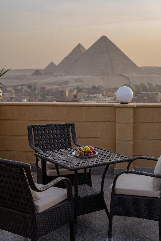 een tafel en stoelen op een balkon met piramides bij Gardenia Pyramids view inn in Caïro