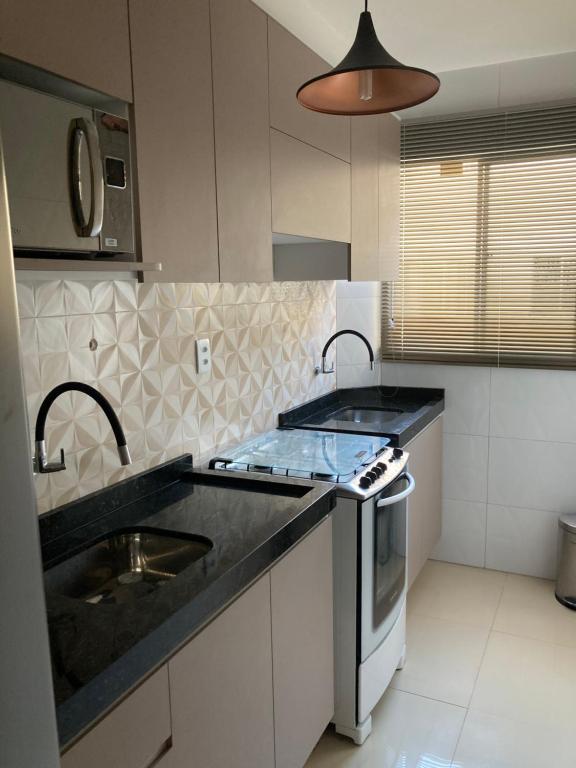 a kitchen with a sink and a stove at Apartamento aconchegante. in Petrolina