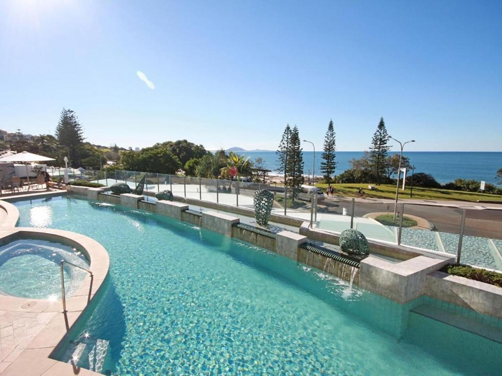 a large swimming pool with the ocean in the background at Oceans 201 luxurious beachfront apartment in Mooloolaba