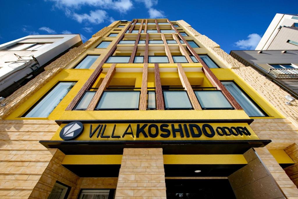 un edificio amarillo con un cartel delante en VILLA KOSHIDO ODORI, en Sapporo