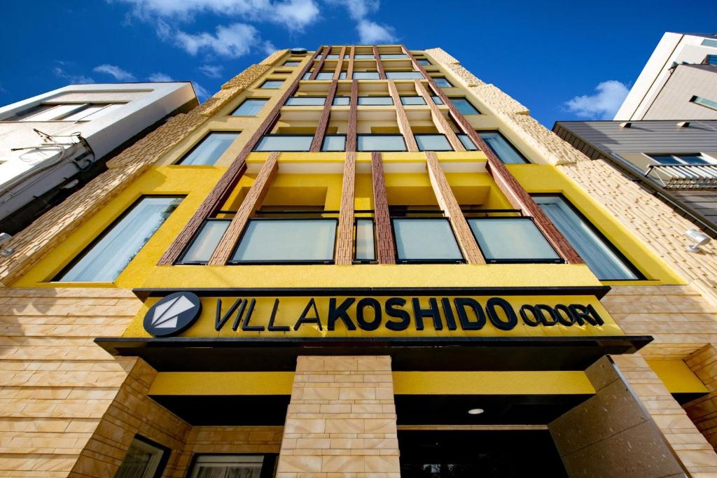 a yellow building with a sign in front of it at VILLA KOSHIDO ODORI in Sapporo