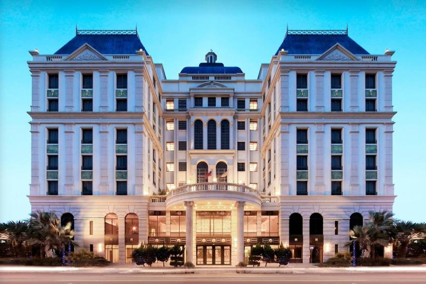 a large white building with palm trees in front of it at Golden Tulip - Aesthetics in Zhunan