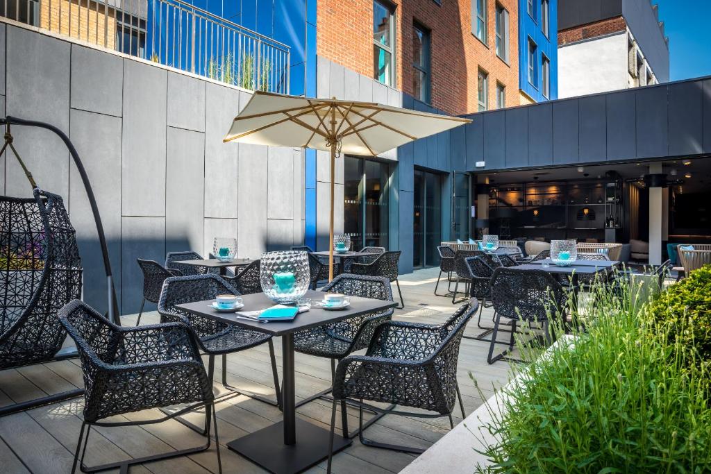 a dining room table with chairs and umbrellas at Motel One Newcastle in Newcastle upon Tyne