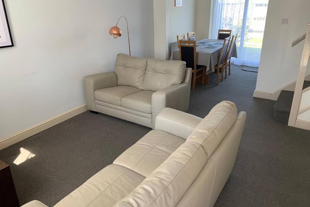 uma sala de estar com um sofá, uma cadeira e uma mesa em 'The Rockingham' 4 double beds, Netflix TVs, WIFI, parking em Corby