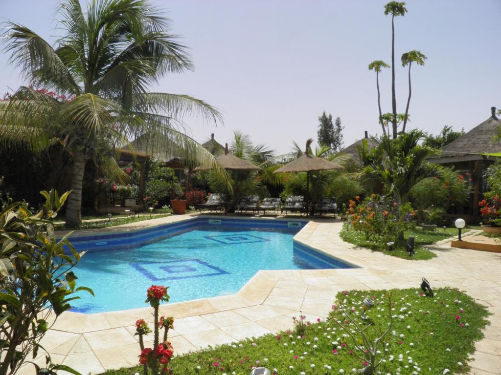 a swimming pool in a yard with palm trees at Le Dakan in Saly Portudal