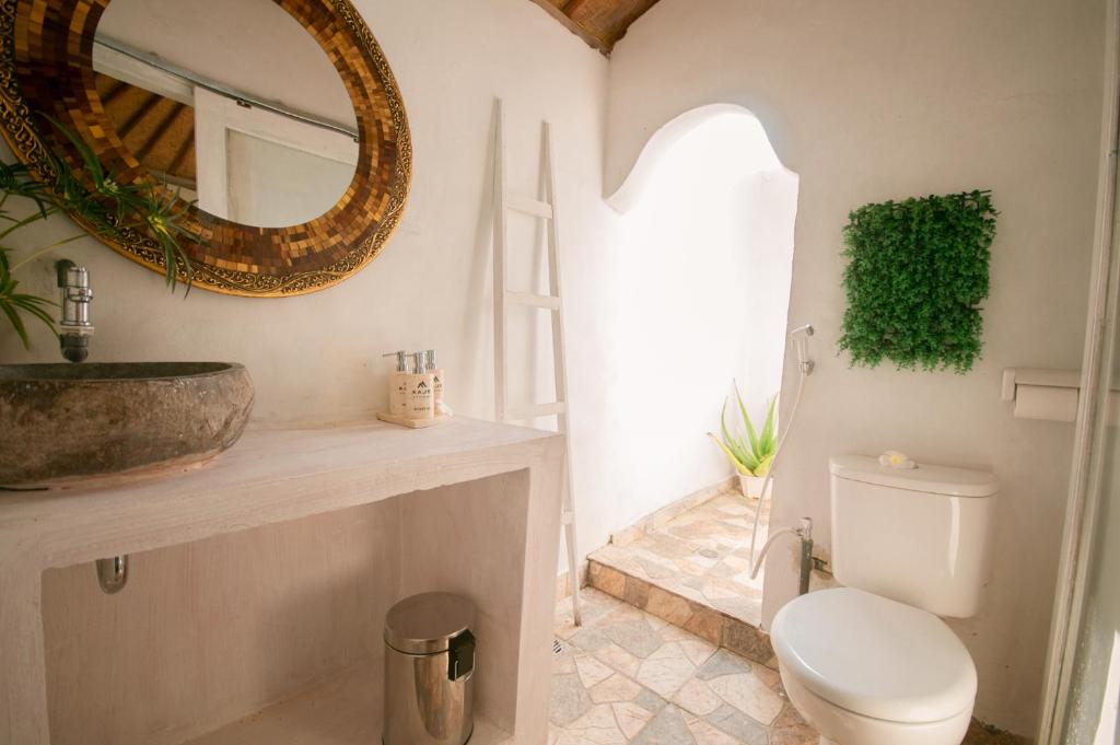 a bathroom with a sink and a toilet and a mirror at kaje cottage & restaurant in Nusa Penida