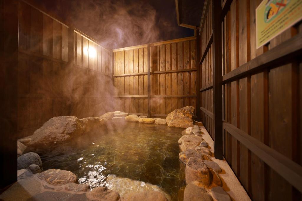 a hot tub in a wooden room with water and rocks at Takanoya Tsuki - Vacation STAY 91942 in Yufuin