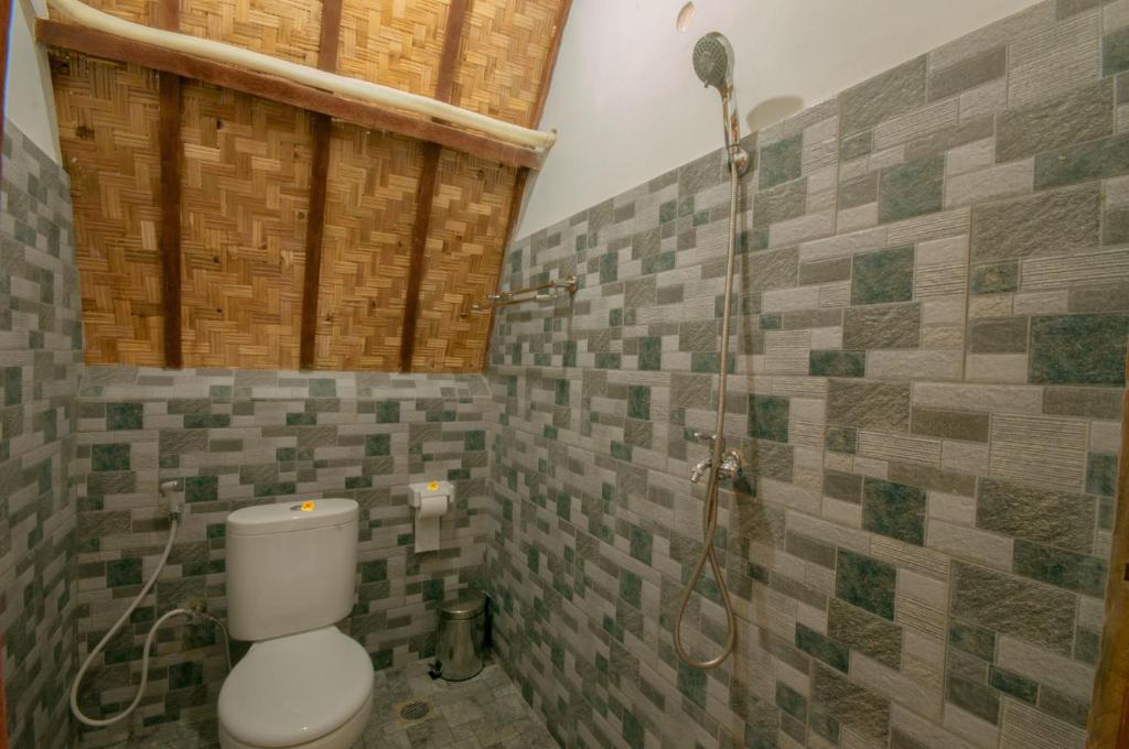 a bathroom with a toilet and a shower with tiles at kaje cottage & restaurant in Nusa Penida