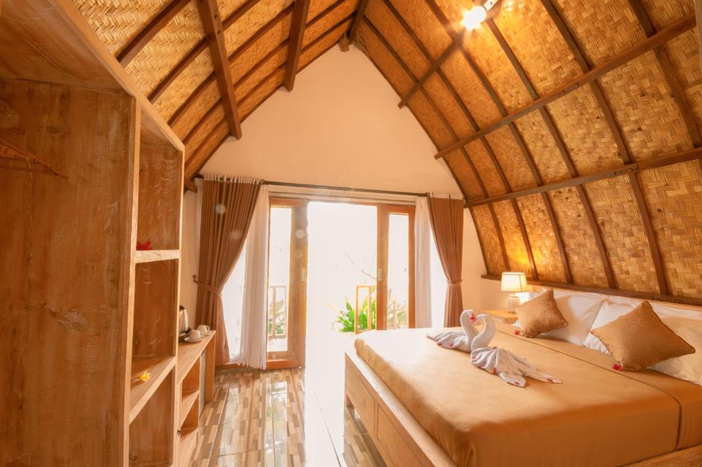a bedroom with a bed with two swans on it at kaje cottage & restaurant in Nusa Penida