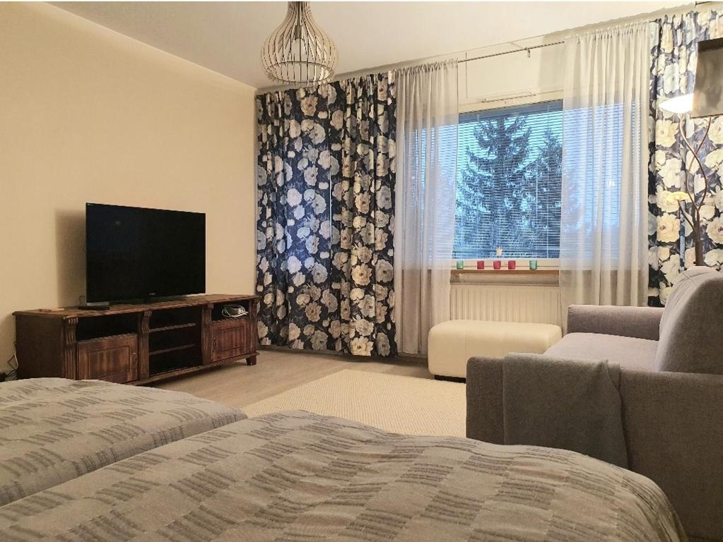 a living room with a bed and a tv and a window at Homely Apartment MILA in Kotka