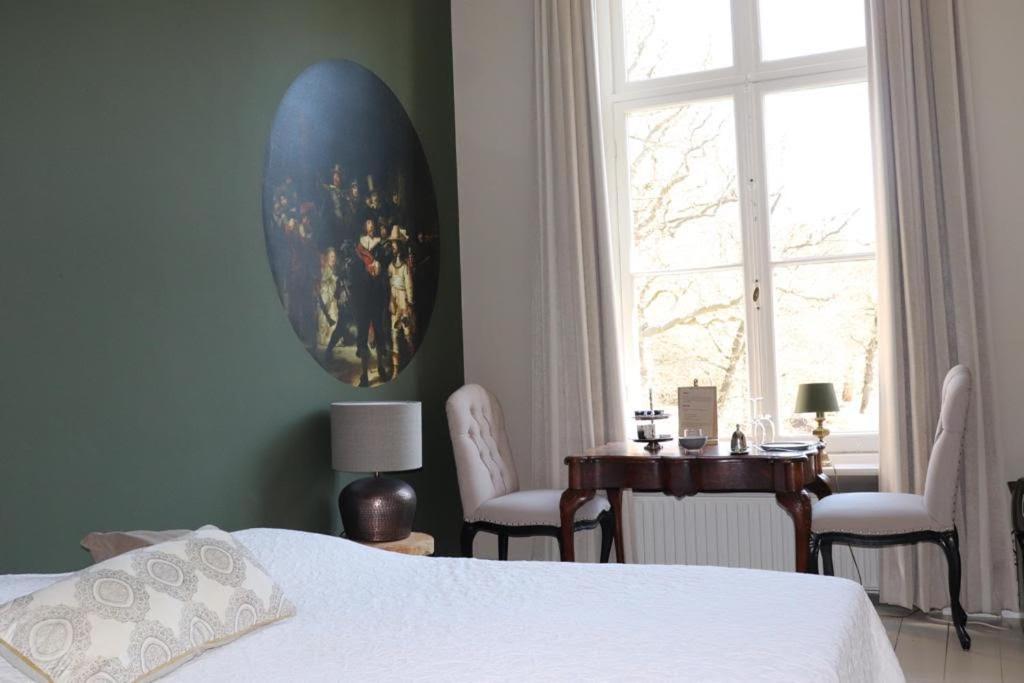 a bedroom with a bed and a table and a window at Hotel Kasteel Hoekelum in Bennekom