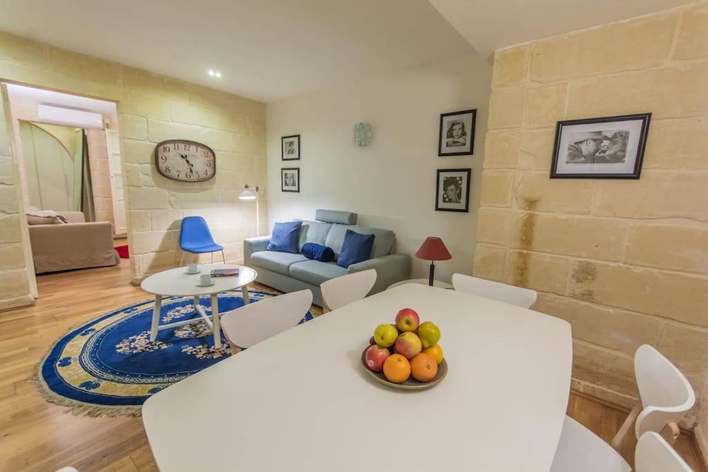 a living room with a table with a bowl of fruit on it at Central Valletta house in Il-Furjana