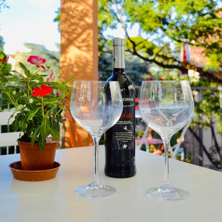 a bottle of wine and two wine glasses on a table at Casa Lighea Mondello - 200 mt dalla spiaggia in Mondello