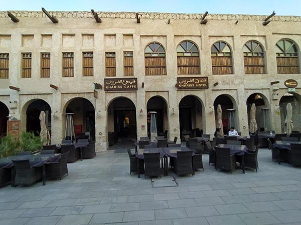 a building with tables and chairs in a courtyard at Al Khariss Hotel in Doha